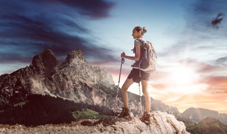 young female hiker with walking sticks near ledge